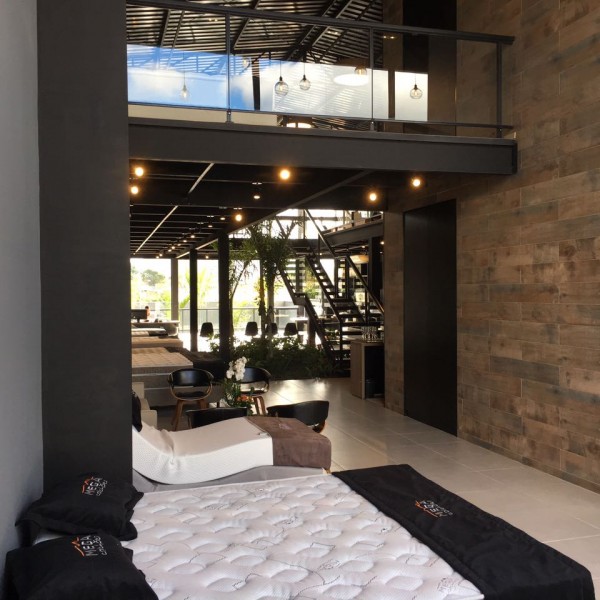 Acesso a loja, vista do mezanino e da escada ao fundo, a planta livre e a conexão entre os ambientes foram as diretrizes do projeto.